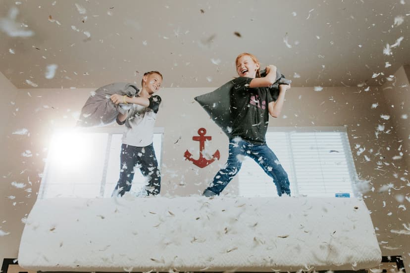 Two boys having a pillow fight, with pillows in mid-air