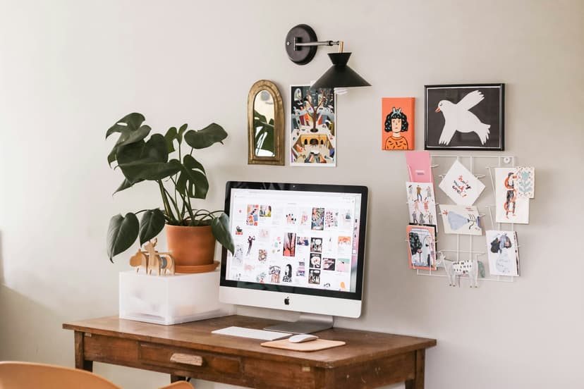 Desk workspace featuring wall art, plants, and a computer